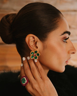 Woman wearing gold earrings with ruby and emeralds